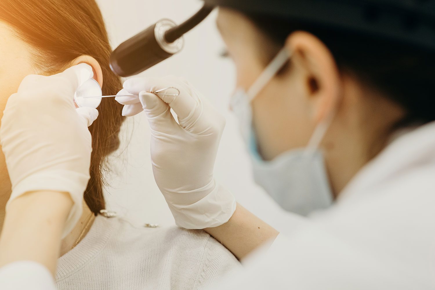 Female Otolaryngologist performing ear exam on female child
