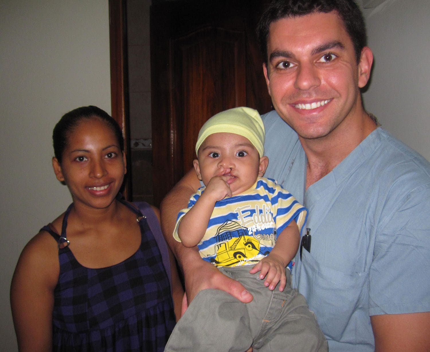 doctor holding child after cleft lip surgery